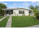Charming single-story home with lush green lawn, palm trees, and a screened in carport at 3213 Normandy Dr, Port Charlotte, FL 33952