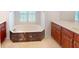 Bright bathroom showcasing a marble-skirted tub, wood cabinetry, and tile flooring at 399 Bal Harbor Blvd, Punta Gorda, FL 33950