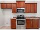 Kitchen showcasing stainless steel oven and microwave, granite countertops, and wood cabinets at 4631 Baynes Rd, North Port, FL 34288
