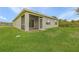 Back exterior view featuring a screened patio, lush lawn, and the home's siding under a blue sky at 616 Posadas Cir, Punta Gorda, FL 33983
