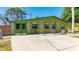 Charming single-story home featuring green exterior with lush landscaping and mature trees at 8035 Hillman Ave, Punta Gorda, FL 33982