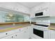 Kitchen with white cabinets, appliances, light countertop and mirror backsplash at 1515 Forrest Nelson Blvd # R201, Port Charlotte, FL 33952