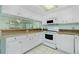 Kitchen with white cabinets and appliances, light countertops, tile flooring, and a mirrored backsplash at 1515 Forrest Nelson Blvd # R201, Port Charlotte, FL 33952