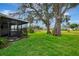 Lush green lawn with a screened in patio surrounded by mature trees at 3 Bermuda Cir # 49, Englewood, FL 34223