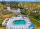 Aerial view of a private pool with a sundeck and poolside cabana overlooking a scenic golf course at 3 Bermuda Cir # 49, Englewood, FL 34223
