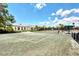 Outdoor tennis court with a green surface, shaded bench and lush landscaping at 3 Bermuda Cir # 49, Englewood, FL 34223