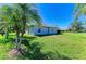 Green backyard featuring grass, palm trees, and a view of the home's exterior at 315 Southland Rd, Venice, FL 34293
