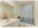 Well-lit bathroom featuring a vanity, toilet, and tub with a patterned shower curtain at 315 Southland Rd, Venice, FL 34293