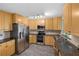 Well-lit kitchen boasts wood cabinetry, granite countertops, stainless steel appliances, and stylish wood-look flooring at 3265 Sunrise Trl, Port Charlotte, FL 33952