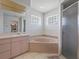 Bathroom featuring a corner soaking tub, privacy glass block windows and a glass door shower at 4461 Baroda Ave, North Port, FL 34287