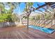 Relaxing pool area with a wooden deck, pergola, and lush tropical landscaping at 5239 Siesta Cove Dr, Sarasota, FL 34242