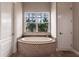 A modern soaking tub in a luxurious bathroom, featuring tiled accents and natural light from a large window at 7440 Riverside Dr, Punta Gorda, FL 33982