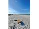 A sandy beach extends towards the sea under a blue sky, with a small wooden table in the foreground at 9400 Little Gasparilla Is # C2, Placida, FL 33946