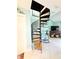 Spiral staircase next to a living room with a blue rocking chair and tiled floors at 9400 Little Gasparilla Is # C2, Placida, FL 33946