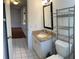 Tiled bathroom featuring a vanity with a granite top, a black framed mirror, and a metal shelving unit at 1051 Forrest Nelson Blvd # M 103, Port Charlotte, FL 33952