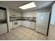 Well-lit kitchen featuring white cabinets and appliances, plus neutral countertops and tile flooring at 1051 Forrest Nelson Blvd # M 103, Port Charlotte, FL 33952