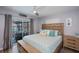Comfortable bedroom features a ceiling fan, wooden floors, and sliding glass door to the screened patio at 129 Barre Nw Dr, Port Charlotte, FL 33952