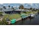 Waterfront home featuring screened-in pool area, dock, boat lift, and lush green lawn at 129 Barre Nw Dr, Port Charlotte, FL 33952