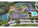 Aerial view of community amenities including tennis courts, pool, clubhouse, volleyball, parking, and lush landscaping at 13049 Creekside Ln, Port Charlotte, FL 33953