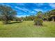 Wide open backyard featuring lush green grass and mature trees, perfect for outdoor entertaining at 13049 Creekside Ln, Port Charlotte, FL 33953