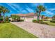 Charming home with a well-manicured lawn and a paved driveway flanked by palm trees and lush bushes at 13049 Creekside Ln, Port Charlotte, FL 33953