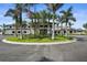 Elegant clubhouse exterior with lush landscaping, palm trees, and an American flag displayed on a sunny day at 14724 Cherry Blossom Way, Punta Gorda, FL 33955