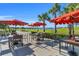 Outdoor tables and chairs with red umbrellas, and palm trees with golf course views at 14724 Cherry Blossom Way, Punta Gorda, FL 33955