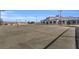 A view of empty tennis court with grey surface, net and surrounded by a black fence at 14724 Cherry Blossom Way, Punta Gorda, FL 33955