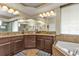 Bathroom with dual sinks, granite countertops, a large mirror, a soaking tub, and tile flooring at 1715 Queen Palm Way, North Port, FL 34288
