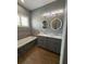 Bright bathroom with double sinks, stone-accented tub, wood-look tile, and plantation shutters at 2031 Basin St, Port Charlotte, FL 33952
