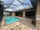 Backyard view of the screened-in pool with brick pavers and an outdoor kitchen area at 2031 Basin St, Port Charlotte, FL 33952