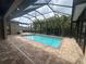 Screened-in pool area featuring brick pavers and tropical palm tree landscaping at 2031 Basin St, Port Charlotte, FL 33952
