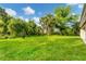 Large backyard features lush green grass and mature trees, offering a private outdoor space at 3841 Cinderella Rd, North Port, FL 34286
