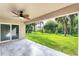 Covered patio with ceiling fan overlooks lush green backyard with mature trees and sliding glass door entrance at 3841 Cinderella Rd, North Port, FL 34286