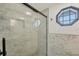Updated bathroom with a glass shower, tiled walls, pebble floor, octagon window and sleek fixtures at 430 Capri Isles Ct, Punta Gorda, FL 33950