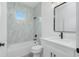 Bathroom featuring marble wall tiling, modern fixtures, and a combined shower and bathtub setup at 4818 Kiska Rd, North Port, FL 34288