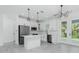 A clean, white kitchen with stainless steel appliances, modern lighting, and a breakfast bar at 4818 Kiska Rd, North Port, FL 34288