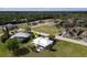 An aerial view shows the neighborhood, green spaces and the house with white roof and screened in porch at 7534 Carissa, Punta Gorda, FL 33955