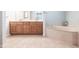 Bathroom featuring double sink vanity with wood cabinets, soaking tub, and tile flooring at 9081 Swiss Blvd, Punta Gorda, FL 33982