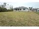 Exterior view showcasing the back of the house with a spacious yard and a covered patio area at 9590 Little Rock St, Port Charlotte, FL 33981