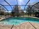 Inviting screened-in pool area with brick pavers, lounge chairs, and a view of the natural surroundings at 10052 Winding River Rd, Punta Gorda, FL 33950