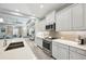 Well-lit kitchen featuring stainless steel appliances, gray cabinets, stone countertops, and seamless access to the living room at 10112 Canaveral Cir, Sarasota, FL 34241