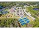 Wide aerial view of a community center, pool, playground, parking and tennis courts with lush trees surrounding at 13096 N Marsh Dr, Port Charlotte, FL 33953