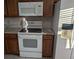 Kitchen featuring a white stove and microwave, next to brown cabinets and a refrigerator at 1340 San Cristobal Ave # 207, Punta Gorda, FL 33983