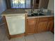 Kitchen featuring a white dishwasher and double sink, next to brown cabinets and a view of the living area at 1340 San Cristobal Ave # 207, Punta Gorda, FL 33983