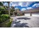 Spacious driveway leads to a charming home with an attached garage and lush, tropical landscaping at 1355 Red Oak Ln, Port Charlotte, FL 33948