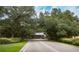 Serene road leading to the community entrance, framed by mature trees and green landscaping at 1355 Red Oak Ln, Port Charlotte, FL 33948