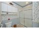 Bathroom featuring tiled shower with glass doors, toilet, and overhead storage at 1474 Red Oak Ln, Port Charlotte, FL 33948