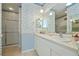 Bathroom featuring dual sinks, large mirrors, decorative wallpaper, and a tiled shower at 1474 Red Oak Ln, Port Charlotte, FL 33948