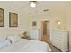 This light-filled bedroom has a ceiling fan and white dressers, with doorway leading to the bathroom at 1474 Red Oak Ln, Port Charlotte, FL 33948